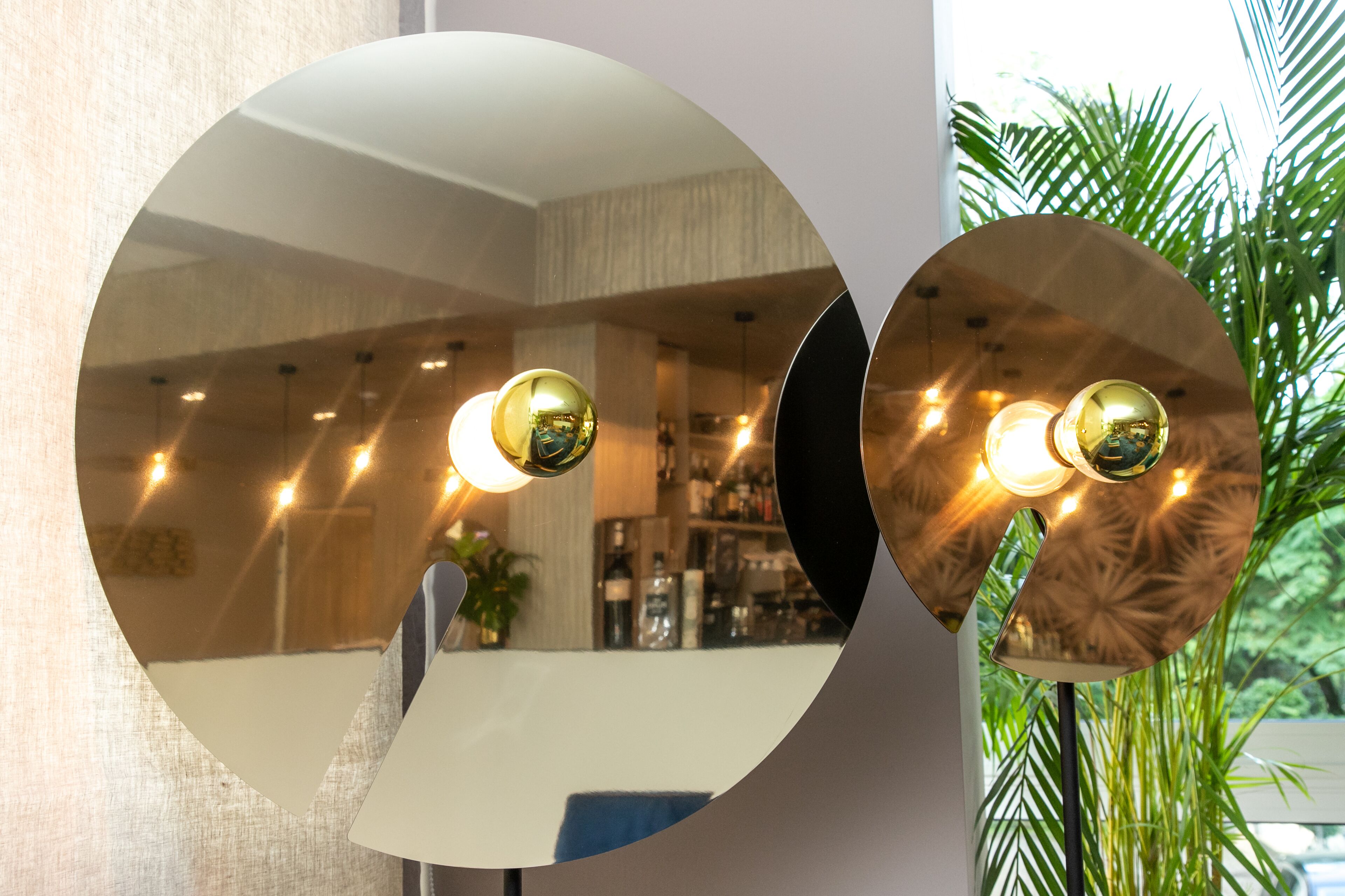 A circular mirror reflecting a room with a table, chairs, and a plant.
