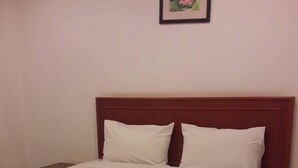 A neatly made bed with white linens and a wooden headboard in a hotel room. - Inter Resort (Nong Saeng)
