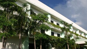A modern building with multiple floors, surrounded by lush greenery and palm trees. - Inter Resort (Nong Saeng)