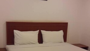 A neatly made bed with white linens, a wooden headboard, and a single framed picture on the wall. - Inter Resort (Nong Saeng)