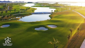 A golf course with a bridge, water hazards, and palm trees. - Minh Duc Hotel (Tuan Chau)