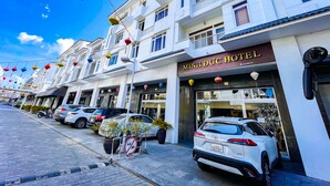 A hotel with a sign reading "MINH BUC HOTEL" and a white car parked in front. - Minh Duc Hotel (Tuan Chau)