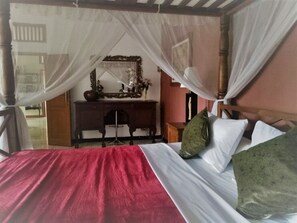 Quarto com cama, escrivaninha e espelho.