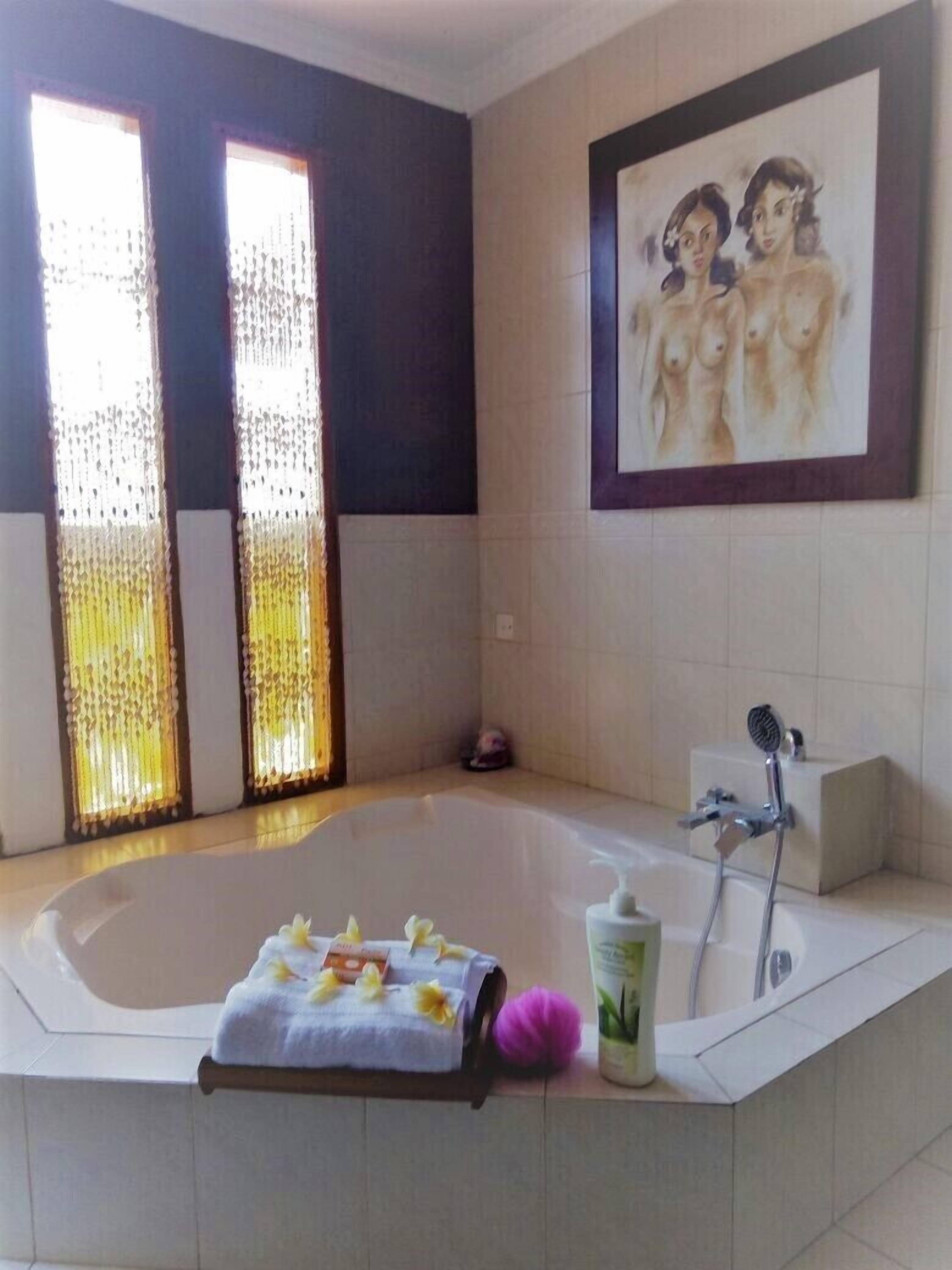 A bathroom with a bathtub, a shower, and a framed painting on the wall.