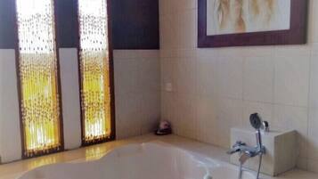 A bathroom with a bathtub, a shower, and a framed painting on the wall.