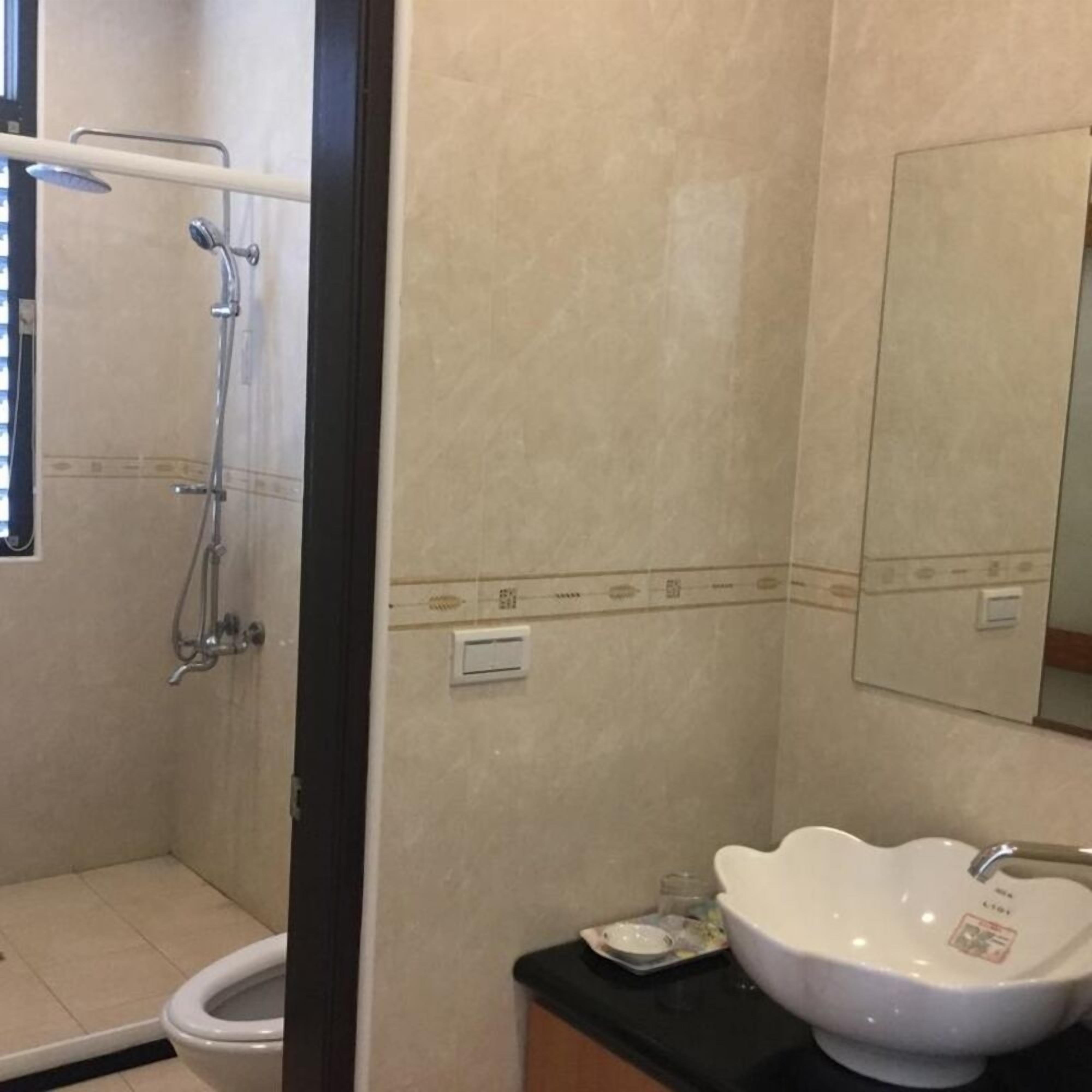 Un baño con inodoro, ducha y lavamanos con espejo.