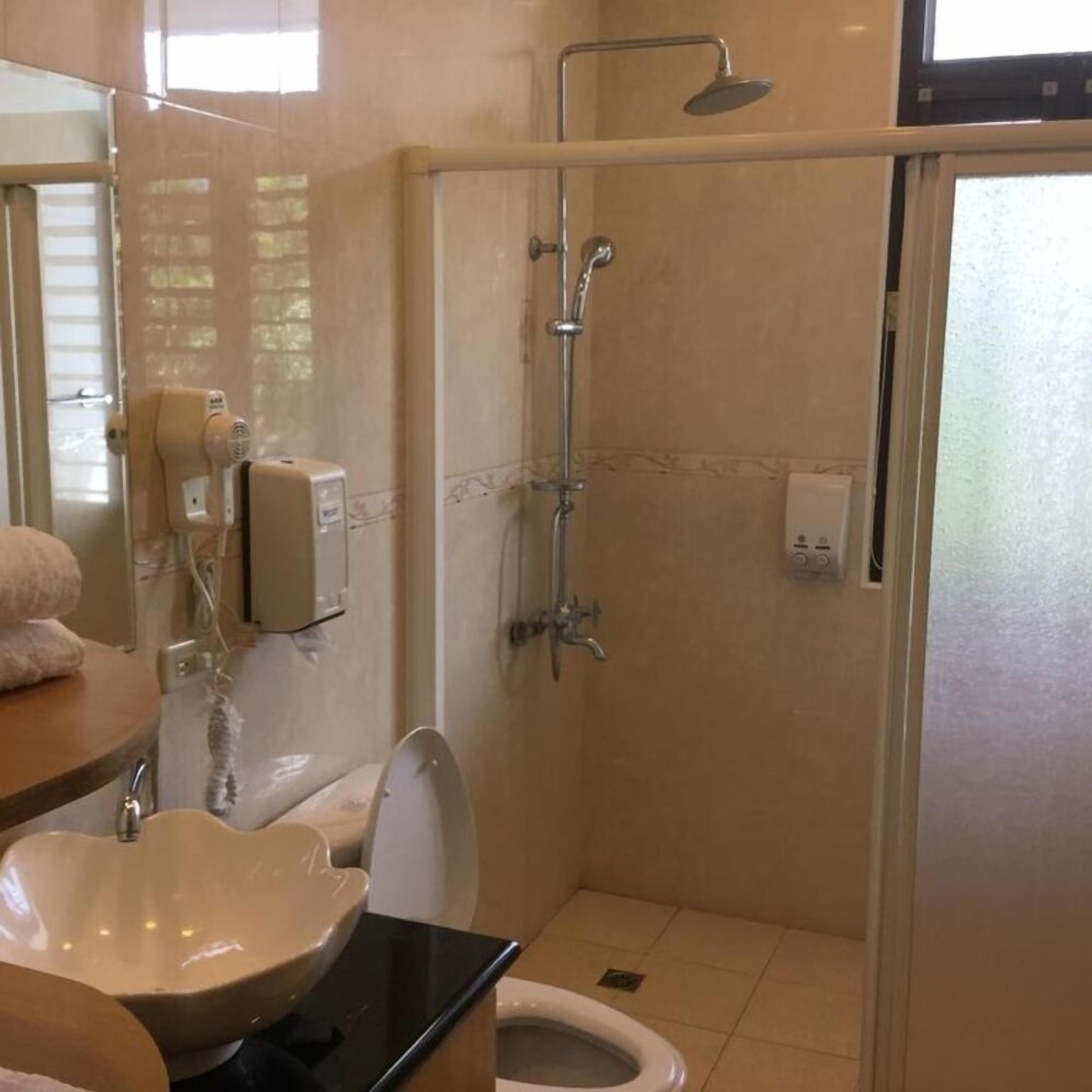 Une salle de bain avec douche, toilettes et lavabo.