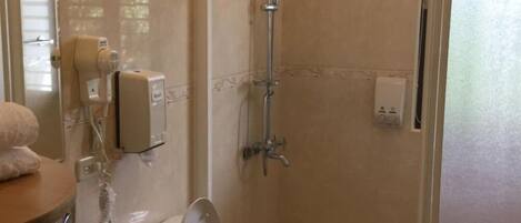 Une salle de bain avec douche, toilettes et lavabo.