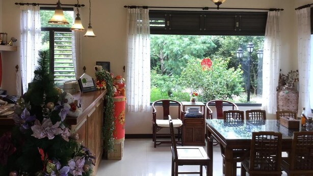 Un comedor con mesa y sillas, una araña y vistas al exterior con vegetación.