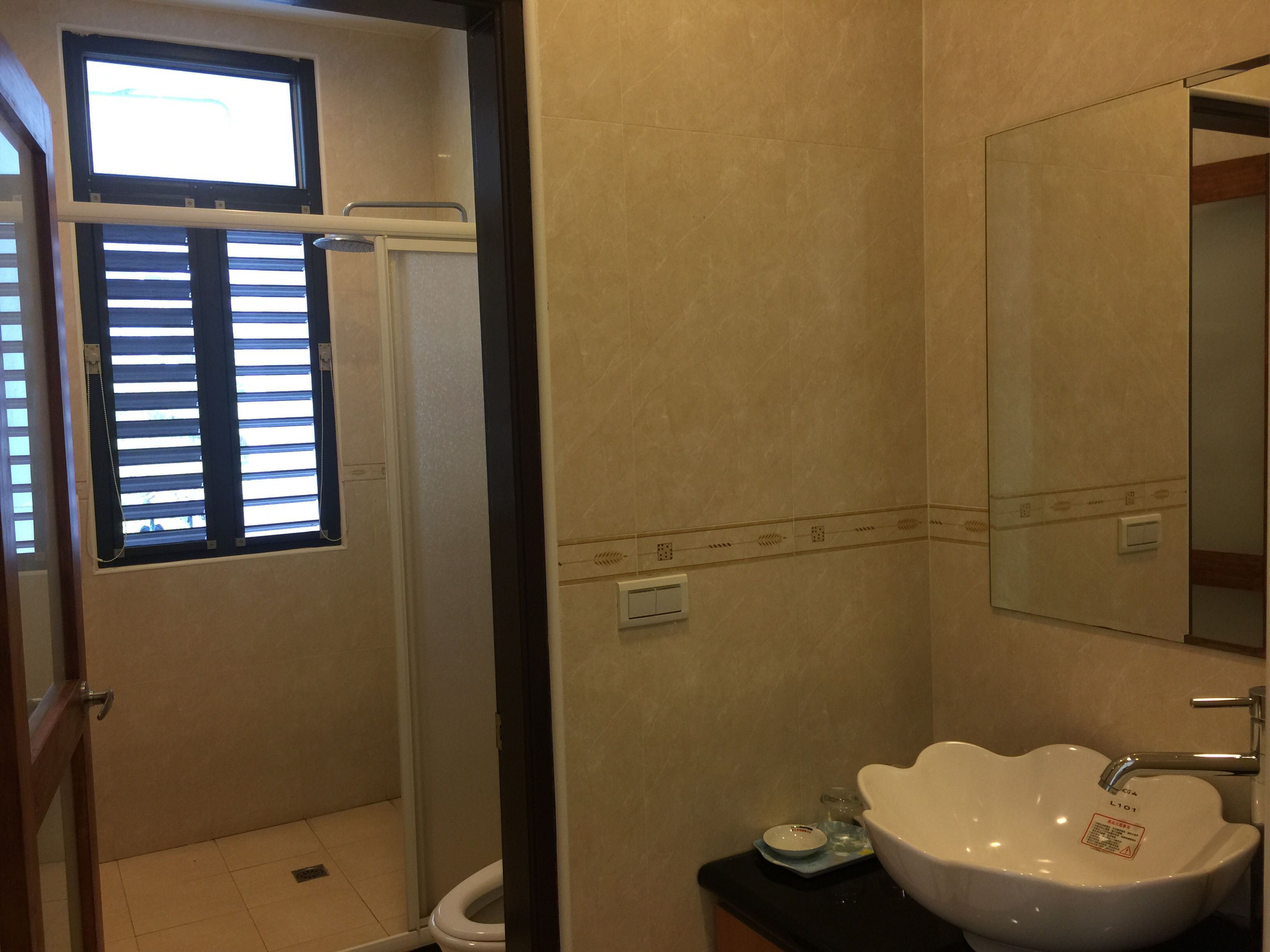 Une salle de bain équipée d’une douche, de toilettes, d’un lavabo et d’une fenêtre avec des stores.