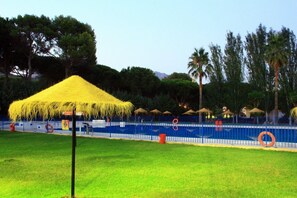 Una piscina al aire libre de temporada, sombrillas
