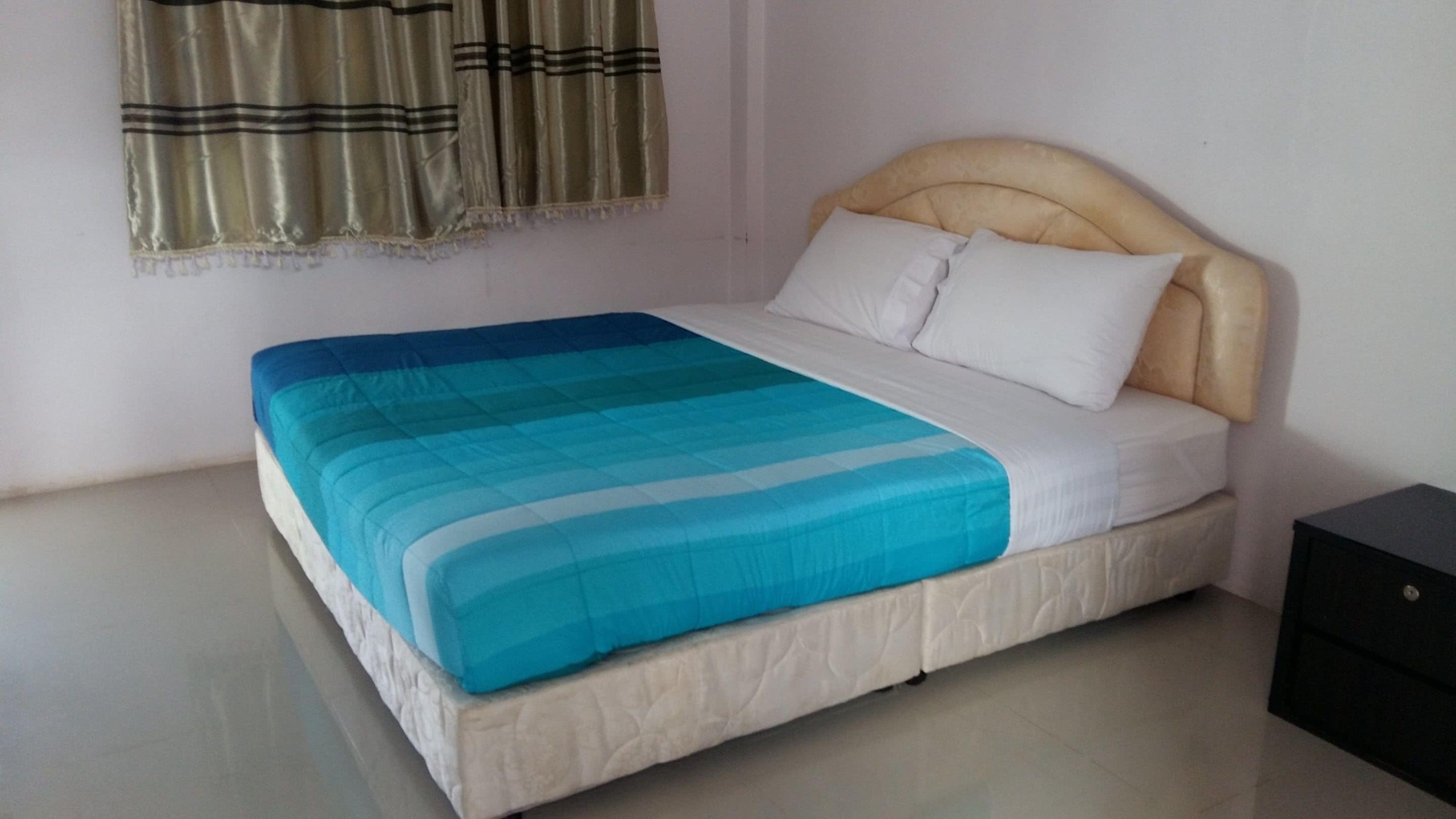 Un letto singolo con una testiera, una coperta a righe blu e bianche e un cuscino bianco.