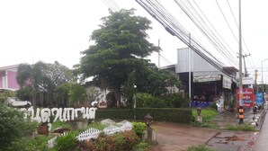 Un camino pavimentado que lleva a un edificio con un cartel en idioma local.
