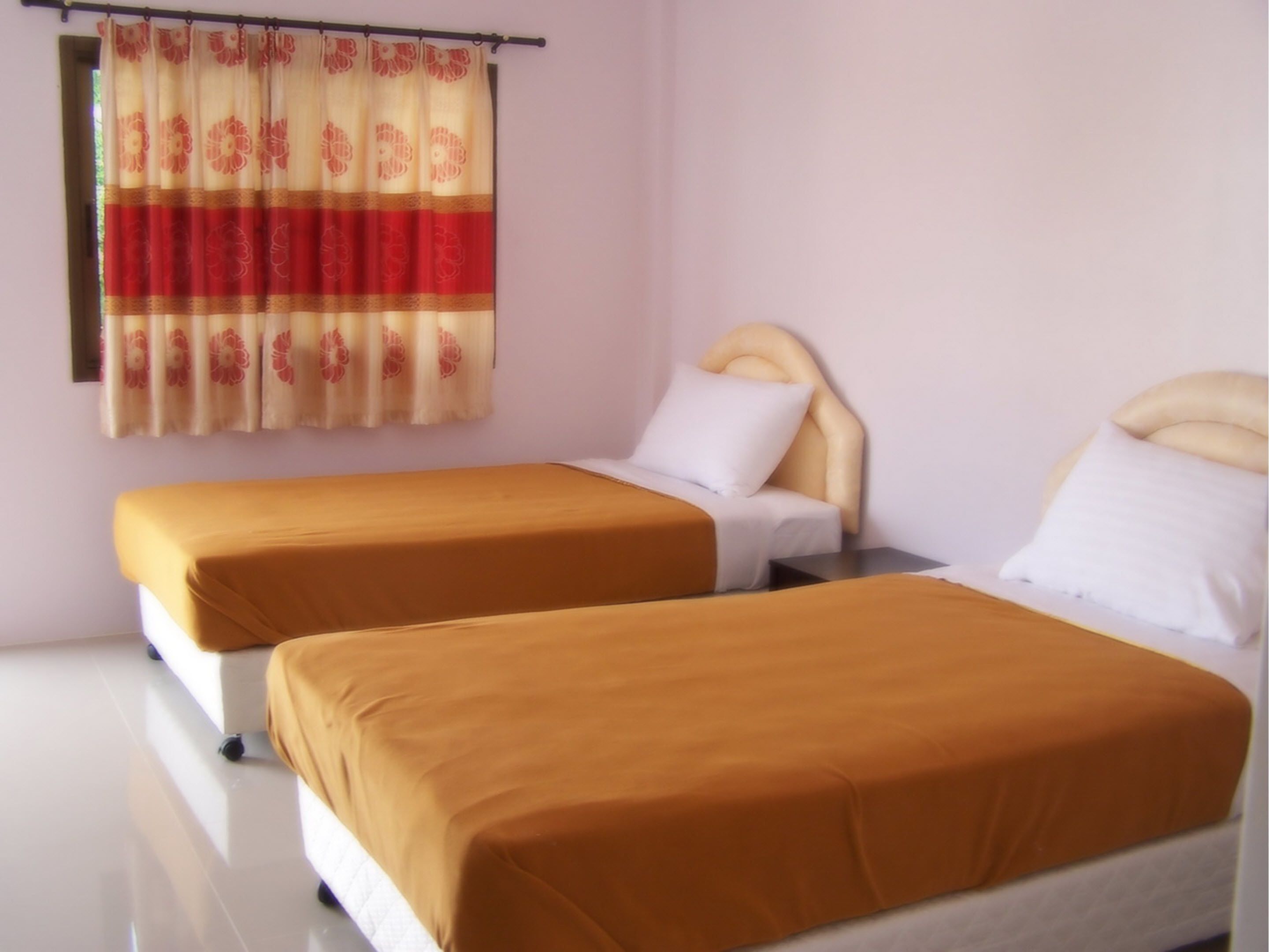 A hotel room with two single beds, each with a headboard and a pillow.