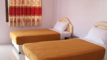 A hotel room with two single beds, each with a headboard and a pillow.