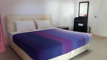 A hotel room with a bed, a nightstand, a black cabinet, and a mirror on the wall.