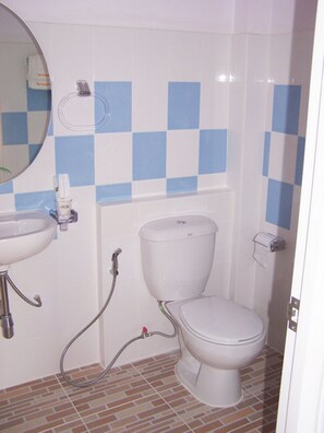 A bathroom with a white toilet, a sink, and a shower. - Bandung Grand (Ban Dung)