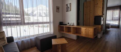 A modern living room with a wooden floor, a sofa, a small table, and a TV.