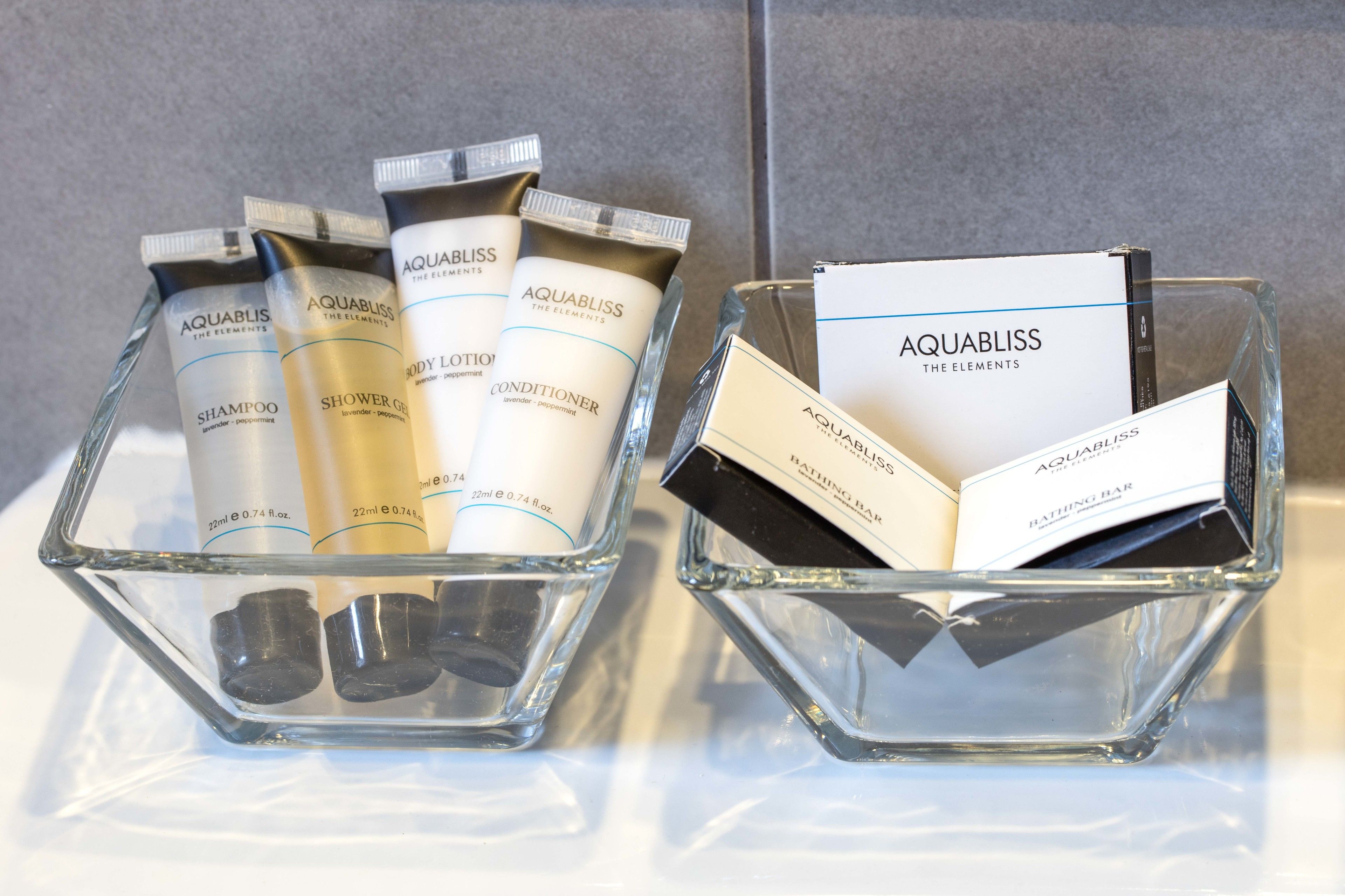 Two glass containers holding Aquabliss toiletries and a booklet.