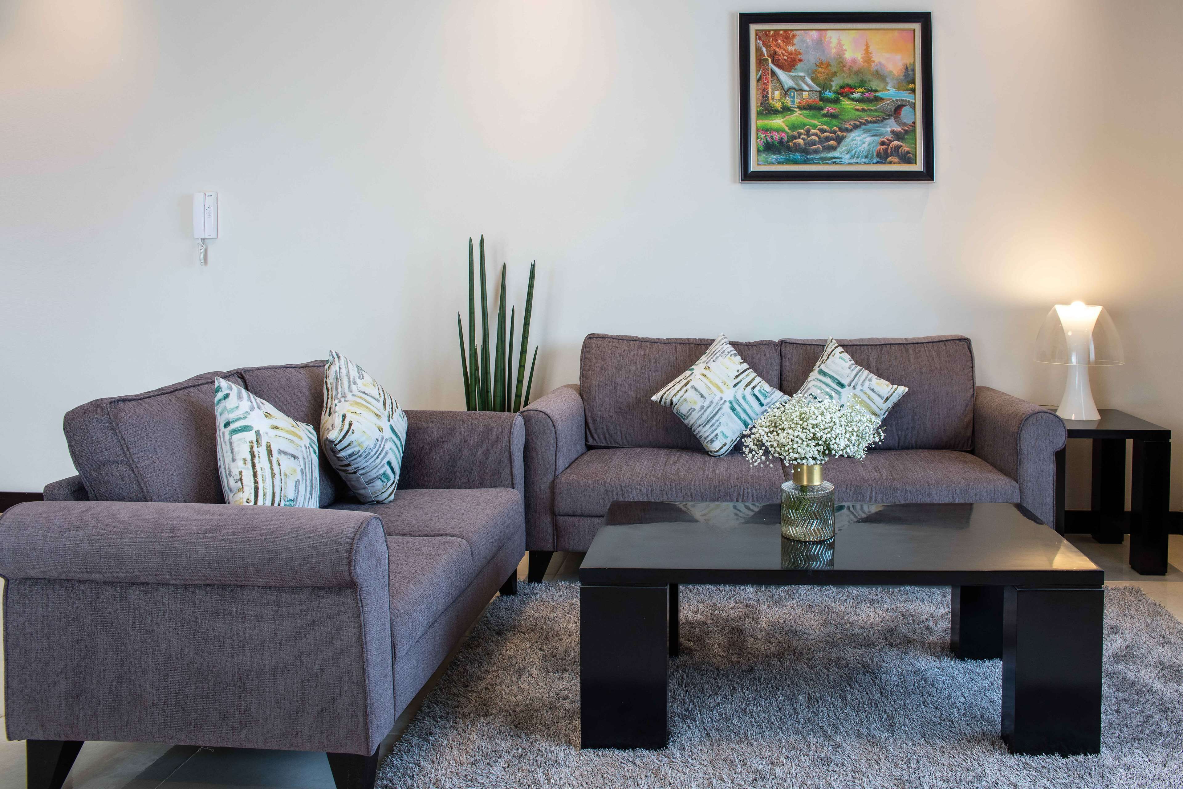 Ein Wohnzimmer mit zwei grauen Sofas, einem schwarzen Couchtisch und einem gerahmten Gemälde an der Wand.