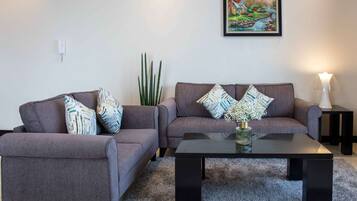 Ein Wohnzimmer mit zwei grauen Sofas, einem schwarzen Couchtisch und einem gerahmten Gemälde an der Wand.