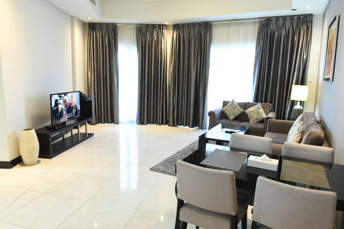 A modern living room with a flat-screen TV, a sofa, a coffee table, and a lamp.
