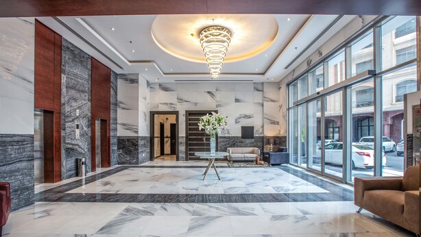 A spacious lobby with marble flooring, a modern chandelier, and large windows offering views of the street. - Loumage S Suites and Spa (Manama)