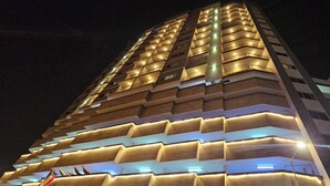 A multi-story hotel with illuminated balconies and a modern architectural design. - Loumage S Suites and Spa (Manama)
