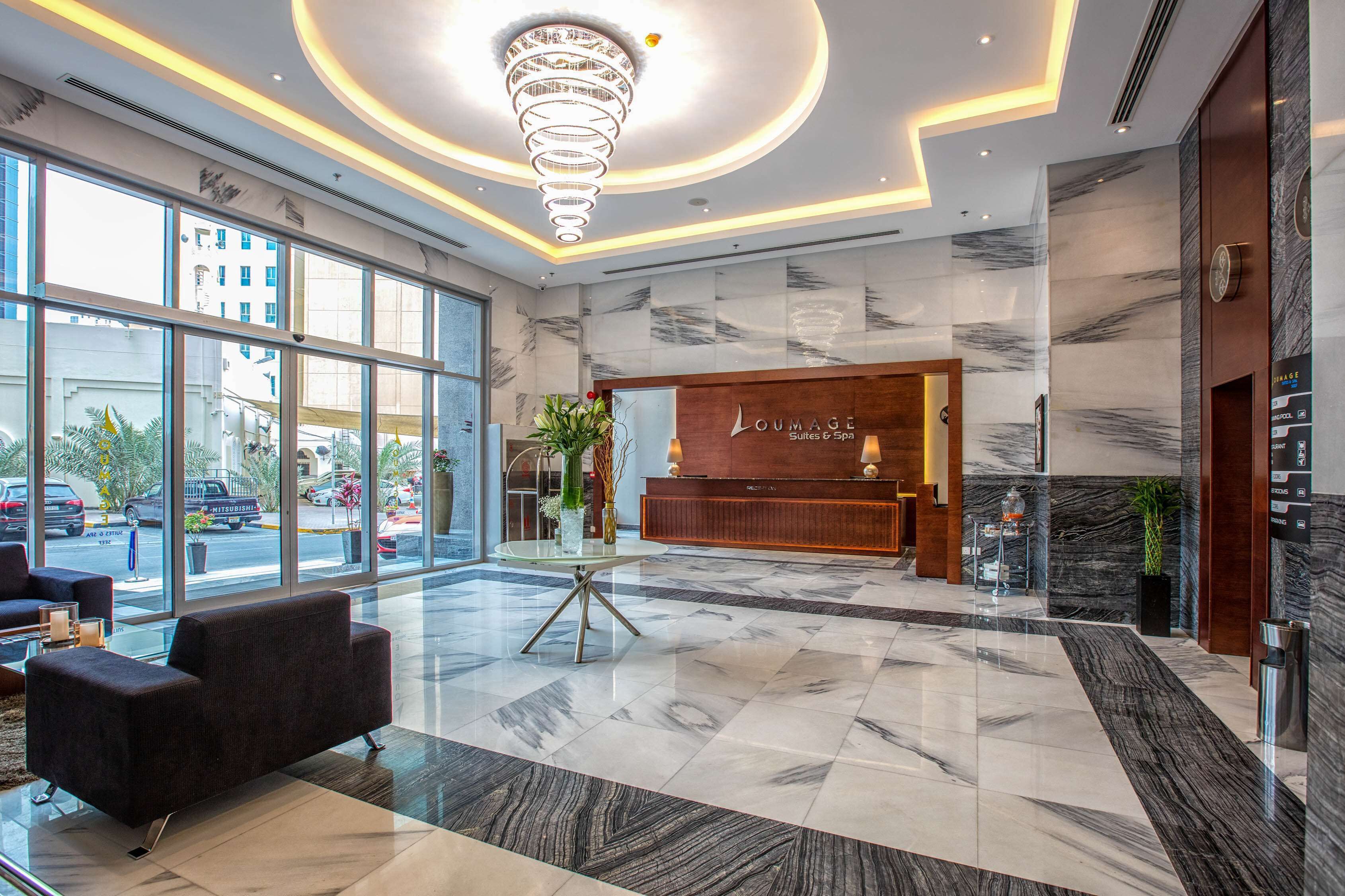 A hotel lobby with a reception desk, seating area, and large windows offering views of the street.