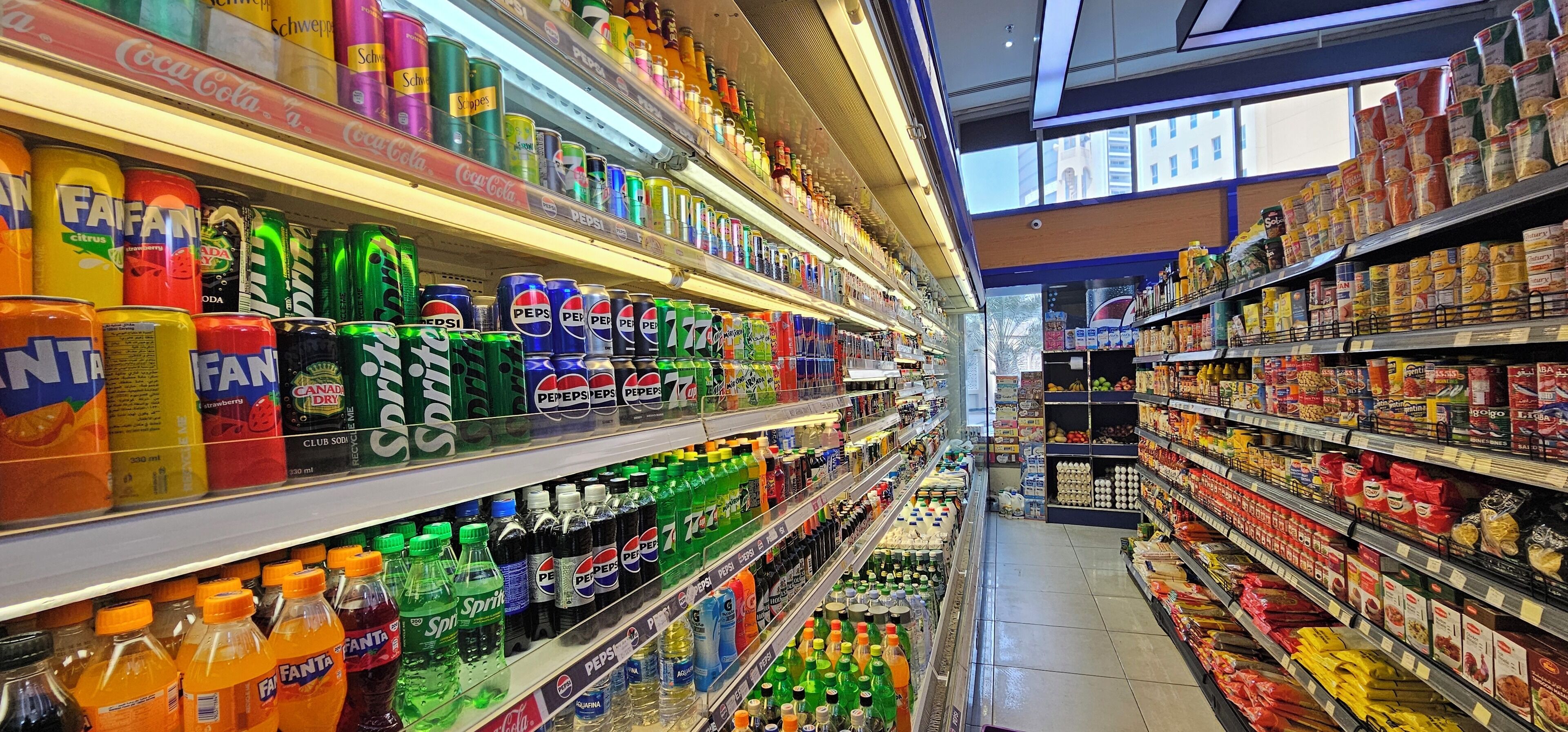 A grocery store aisle with shelves stocked with various beverages and snacks.