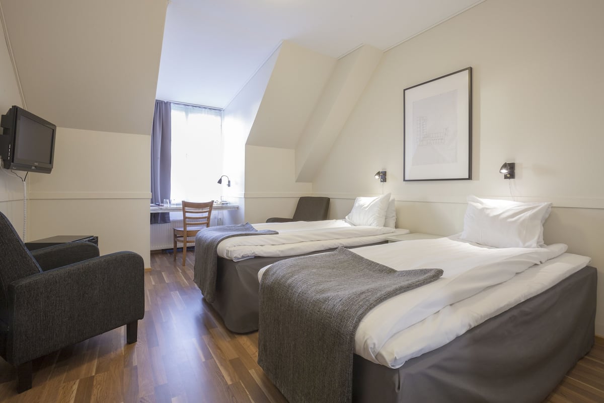 Ein Hotelzimmer mit zwei Betten, einem Schreibtisch, einem Stuhl und einem Fernseher.
