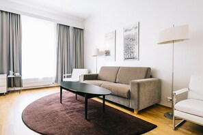 Uma sala de estar moderna com sofá, mesa de centro, luminária e obras de arte na parede.
