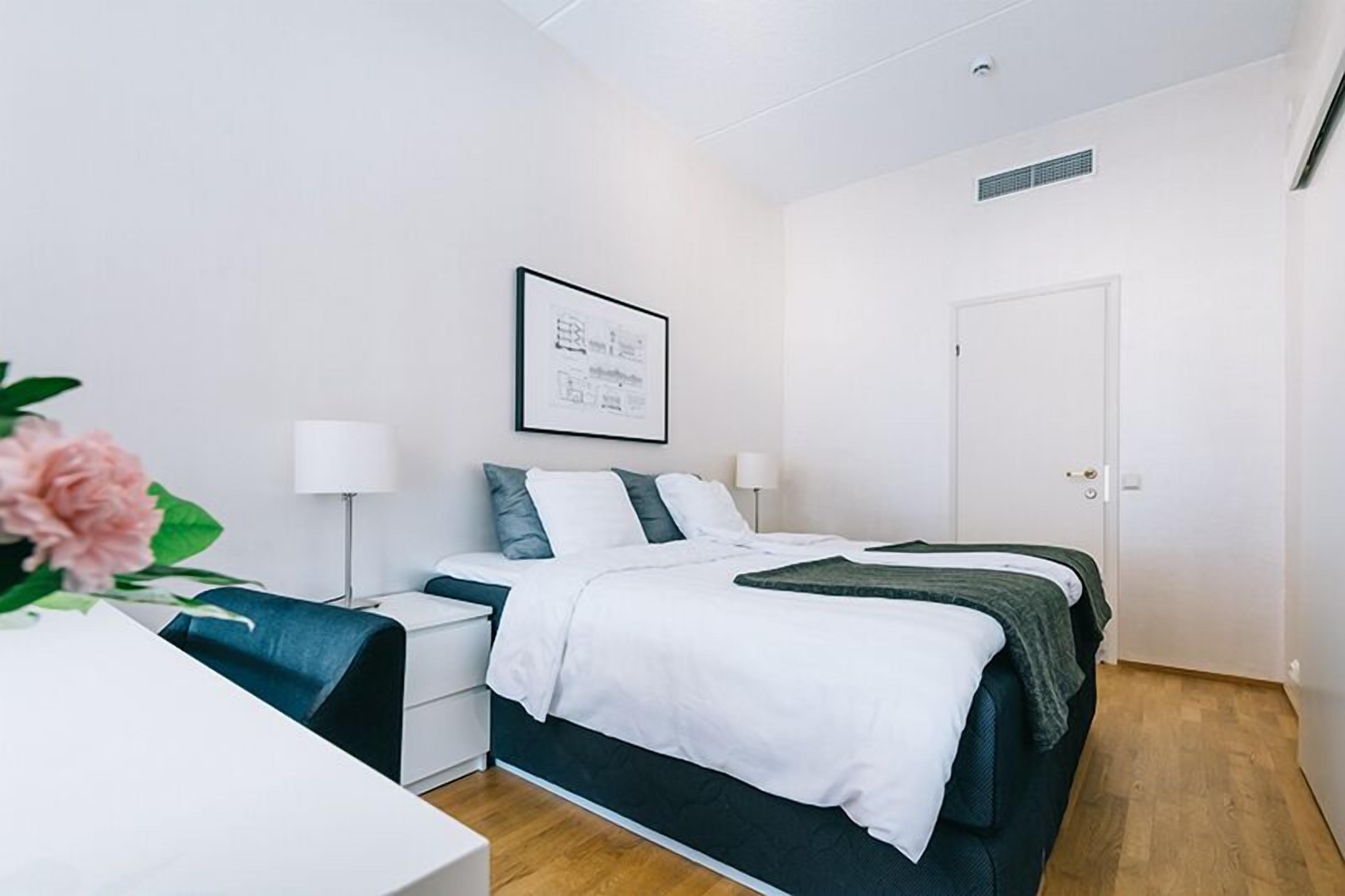 Un dormitorio moderno con cama, mesitas de noche, un escritorio y una silla.