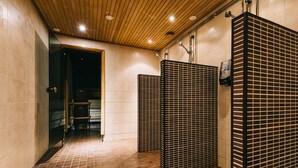 A public restroom with tiled floors, wooden ceiling, and metal partitions.