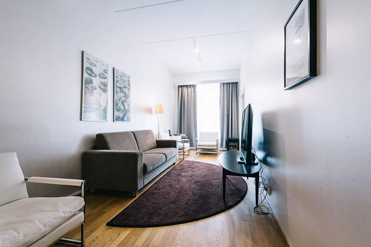 Ein modernes Wohnzimmer mit einer Couch, einem Sessel, einem Fernseher und Kunstwerken an den Wänden.