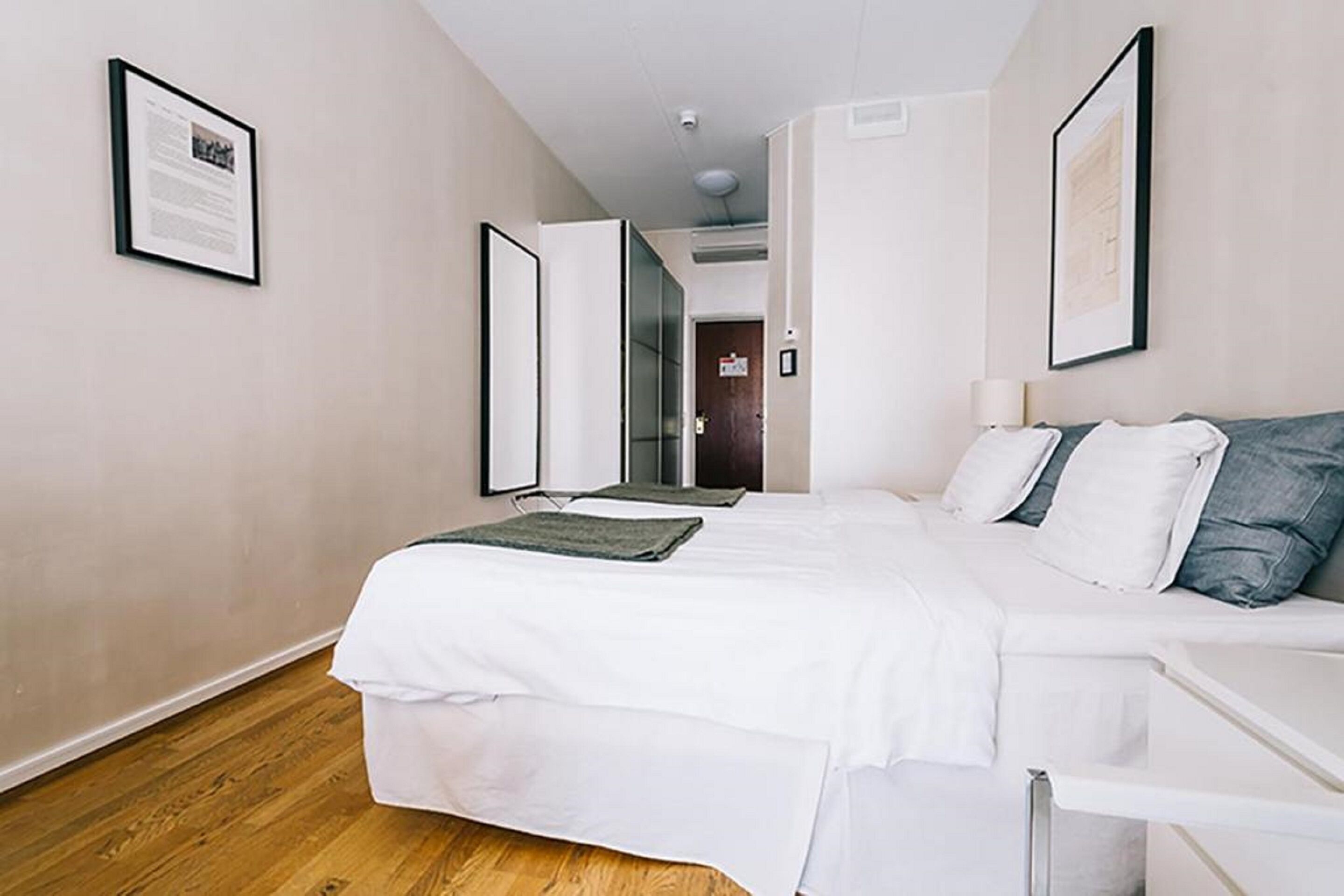 Een moderne hotelkamer met een groot bed, een nachtkastje en uitzicht op de gang.