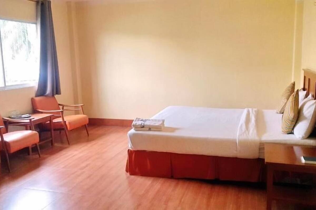 A hotel room with a bed, a desk, a chair, and a television.