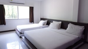 A hotel room with two single beds, a large window with curtains, and an air conditioning unit on the wall. - Sri Chumphon Hotel (Chumphon)