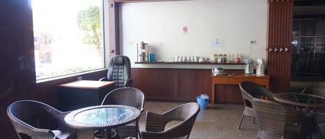 Una habitación con muebles de mimbre, una pizarra y una zona de bar con diversos objetos.