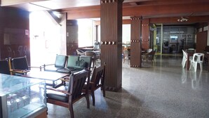 A spacious lobby with wooden furniture, a glass display case, and large windows allowing natural light. - Sri Chumphon Hotel (Chumphon)