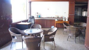 A room with wicker furniture, a glass table, and a ceiling fan. - Sri Chumphon Hotel (Chumphon)