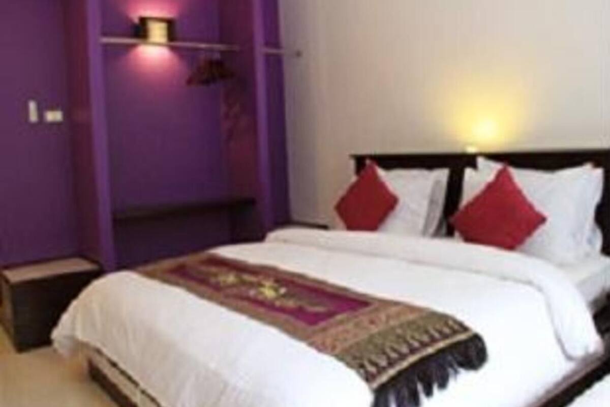 A bedroom with a bed, a bedside table, a wall-mounted light, and a wall decoration.
