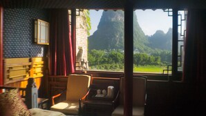 Una habitación con una cama, una silla, una mesa y vistas a un paisaje montañoso.