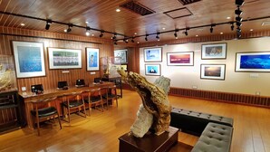 Una habitación amplia con paneles de madera, un área de estar central con una gran escultura y paredes decoradas con fotografías enmarcadas.
