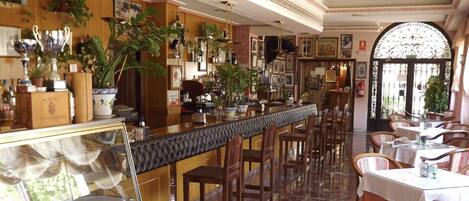 A bar area with wooden paneling, potted plants, and a long counter.