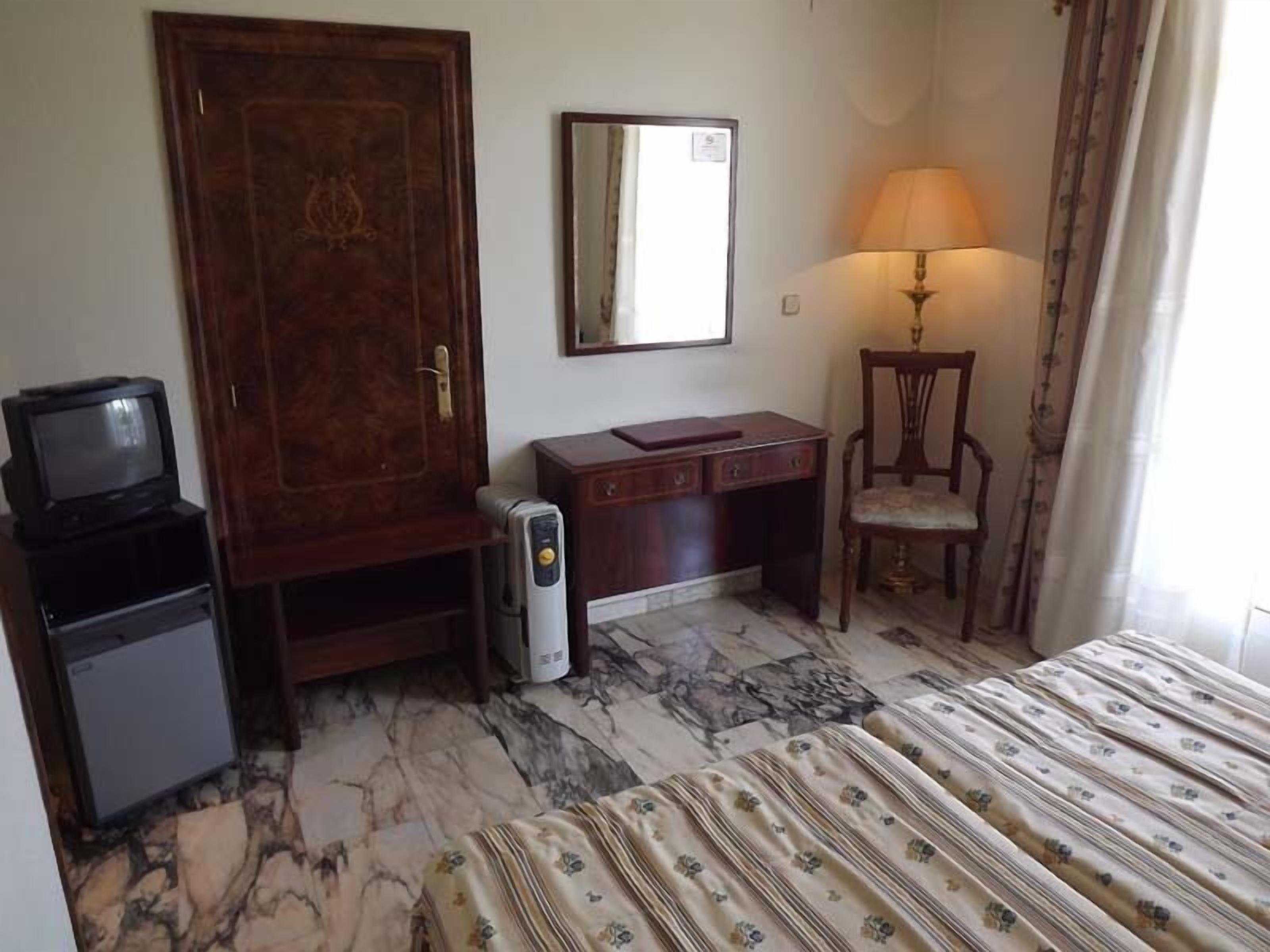 Una habitación de hotel con una cama, un escritorio, una silla, un televisor y un calentador.