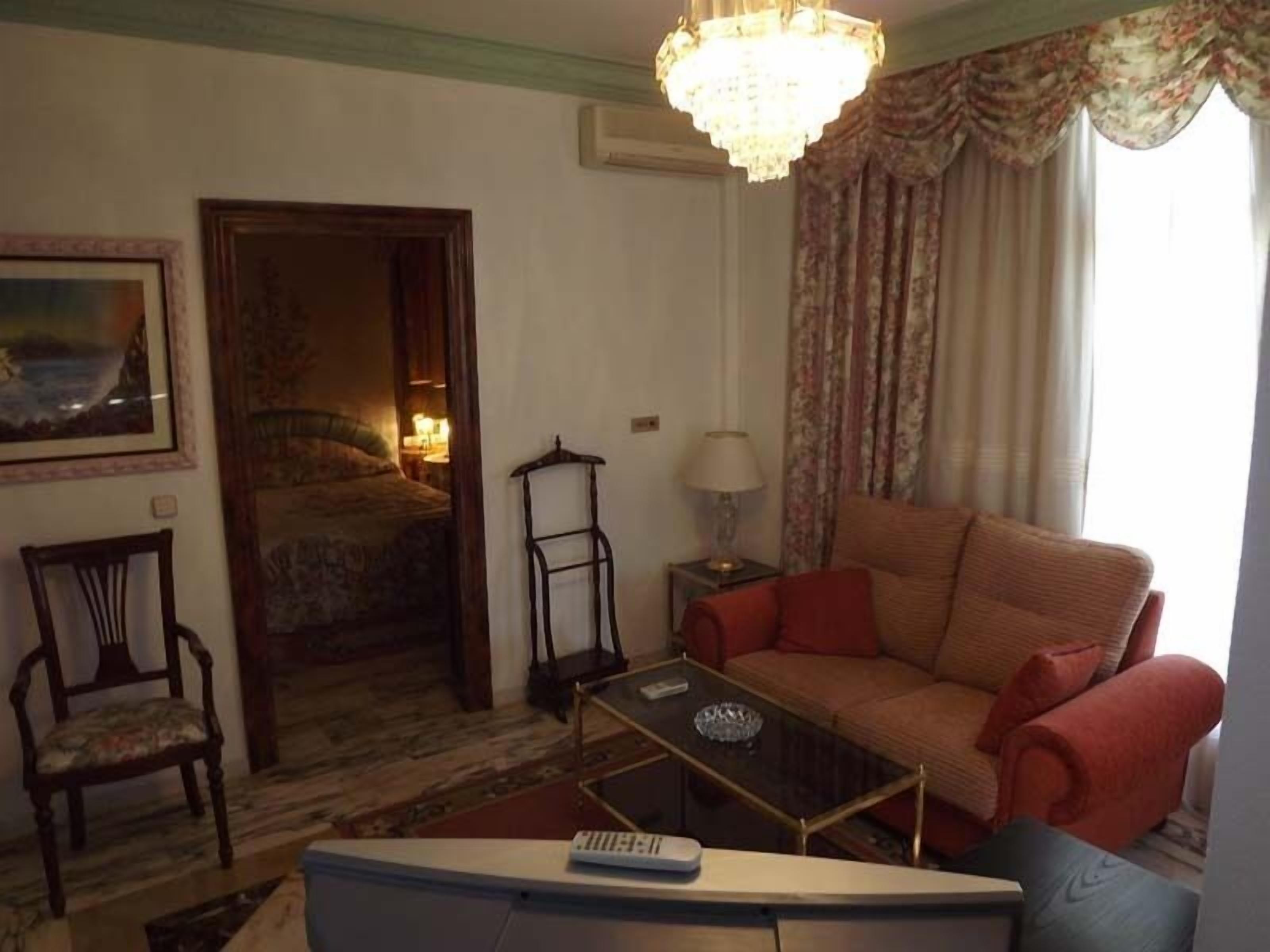 Una sala de estar con sofá, mesa de centro, sillón, lámpara y candelabro.