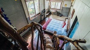 A bedroom with a bed, a small window, a wooden chair, and a staircase. - Yunnan Homestay (Ren'ai)