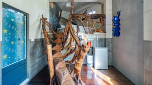 A modern interior with a unique wooden sculpture, a blue star-patterned door, and a minimalist kitchen area. - Yunnan Homestay (Ren'ai)