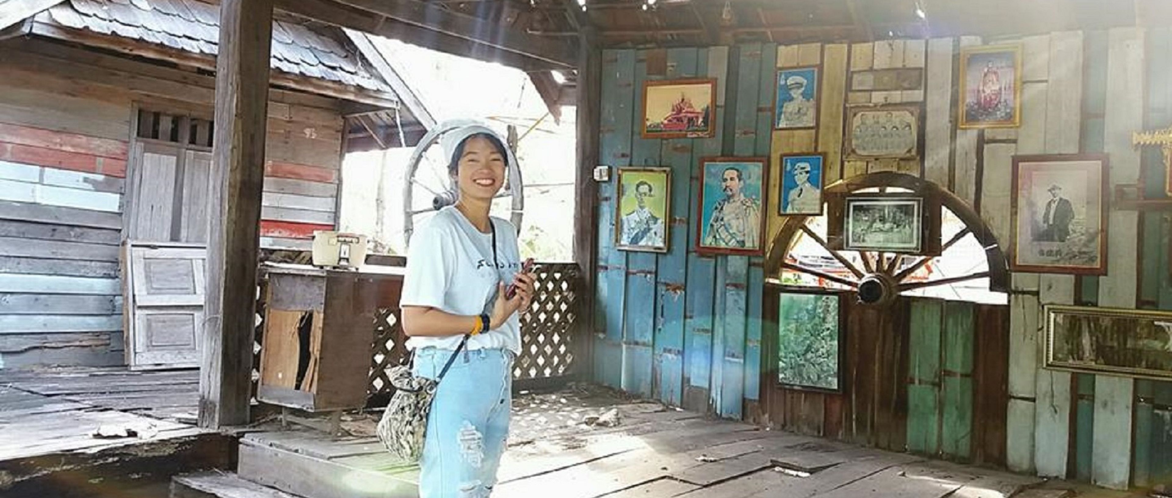 A rustic wooden building with a corrugated metal roof, a wooden door, and a wall adorned with framed pictures.